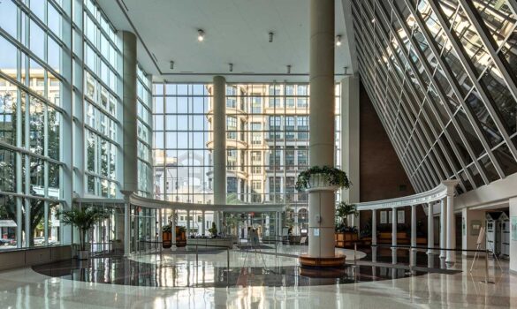 The lobby of a large office building with large windows.
