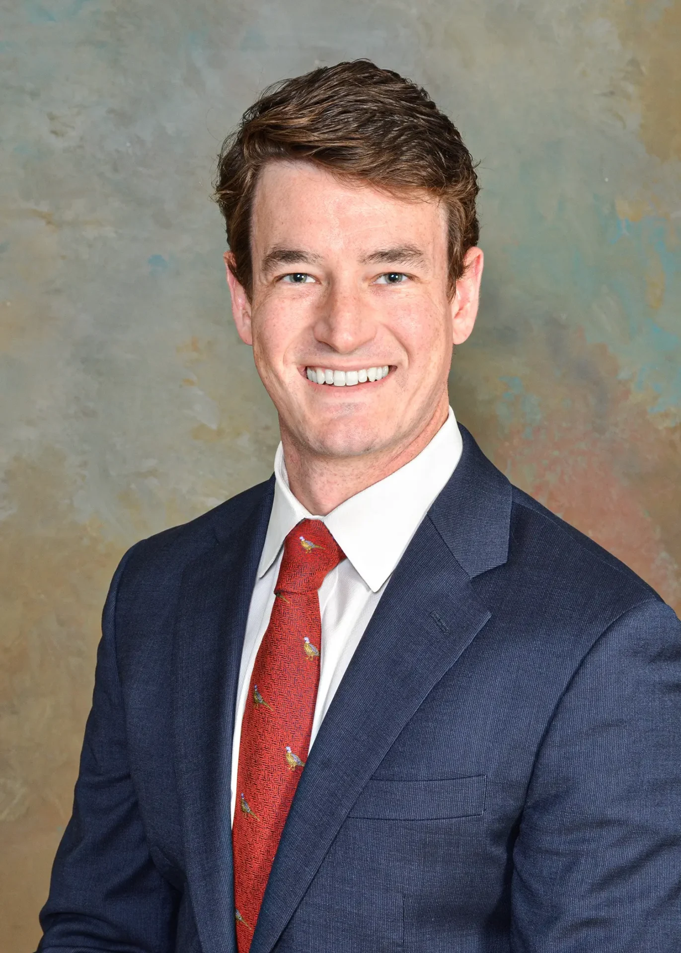 Smiling man in blue suit and red tie.